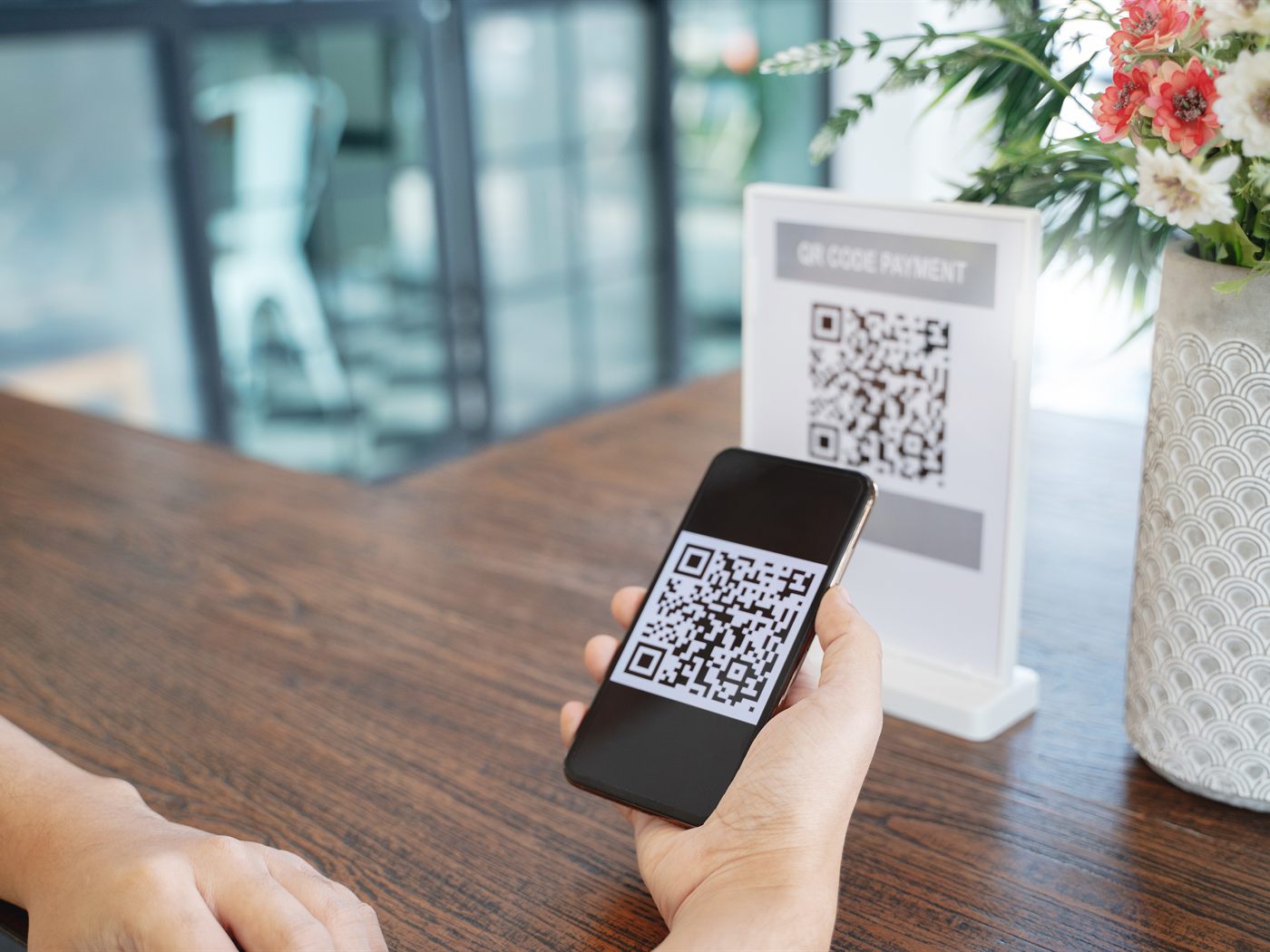 Πελάτης πληρώνει σκανάροντας QR code με το κινητό του στο ταμείο καταστήματος